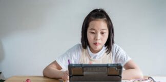 Jak przygotować się do lekcji online, żeby naprawdę się uczyć, a nie tylko „być” na kamerce Dziewczyna uczy się z tabletem przy biurku, obok przekąski