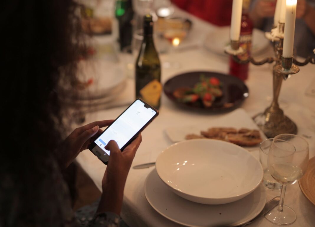 Kobieta korzystająca ze smartfona przy stole w restauracji przy świecach